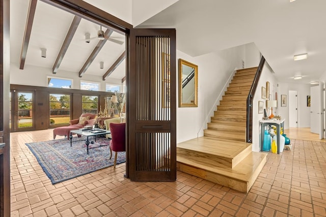 interior space with beamed ceiling, brick floor, and a ceiling fan