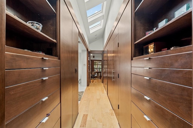 walk in closet with lofted ceiling with skylight and light wood-type flooring