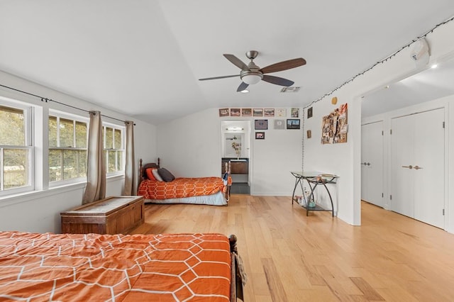 bedroom with light wood-style floors, visible vents, vaulted ceiling, and ceiling fan