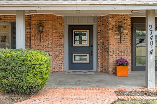 doorway to property with covered porch and brick siding