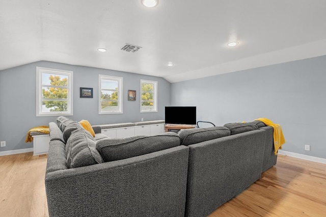 living room featuring light wood-type flooring, visible vents, lofted ceiling, and baseboards