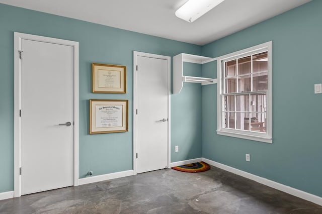 unfurnished bedroom with concrete floors and baseboards