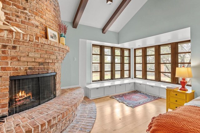 bedroom with lofted ceiling with beams, a fireplace, and wood finished floors