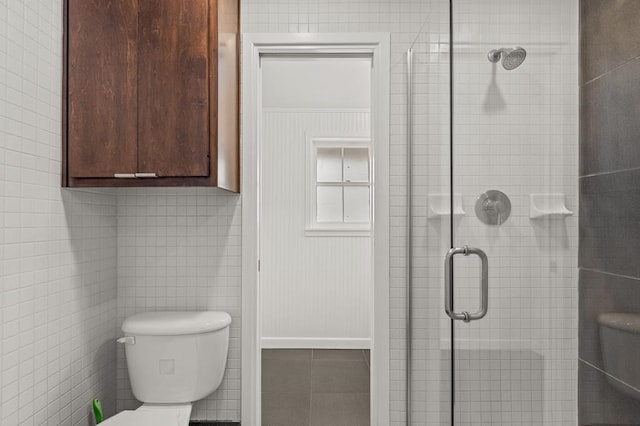 full bath with a stall shower, tile patterned floors, toilet, and tile walls