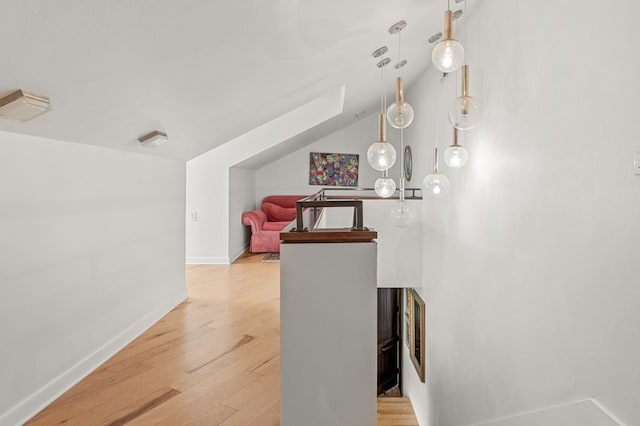 hall with lofted ceiling, light wood-style flooring, and baseboards