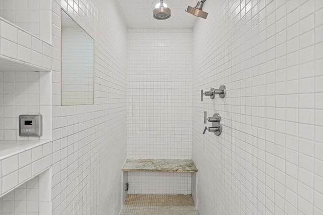 full bathroom featuring a tile shower and tile walls