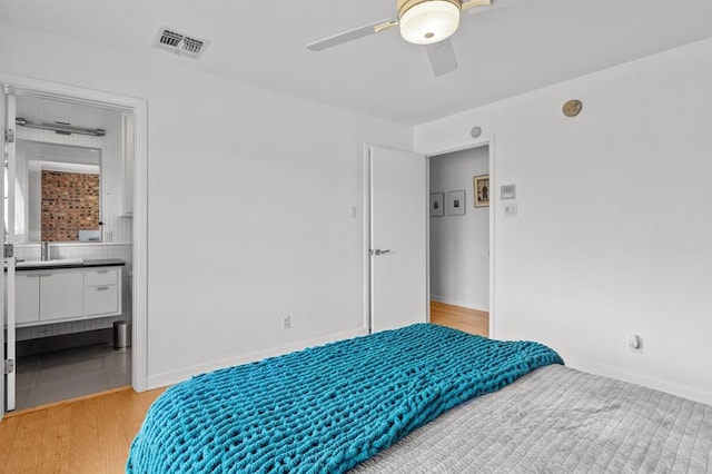 bedroom featuring visible vents, ceiling fan, ensuite bath, light wood-type flooring, and baseboards