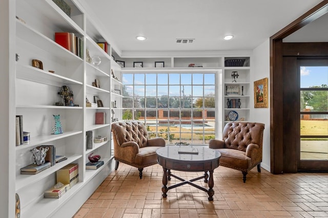 living area with brick floor, recessed lighting, and visible vents