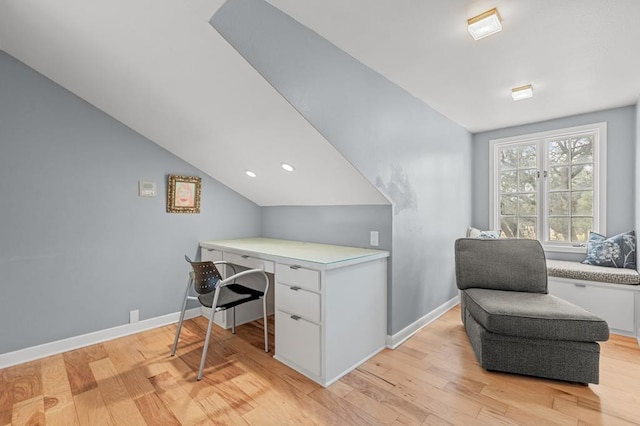 office space with light wood-type flooring, baseboards, built in desk, and lofted ceiling