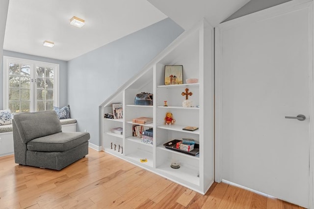 sitting room featuring light wood finished floors, built in shelves, and baseboards