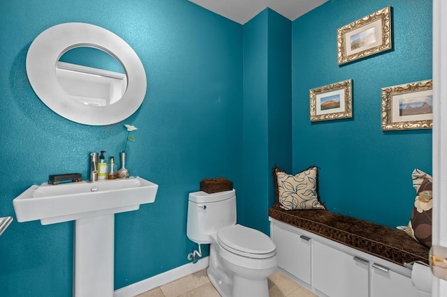 half bathroom featuring baseboards, a sink, toilet, and tile patterned floors