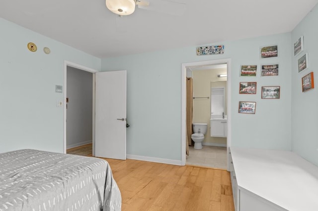 bedroom featuring light wood-style floors, ensuite bath, and baseboards