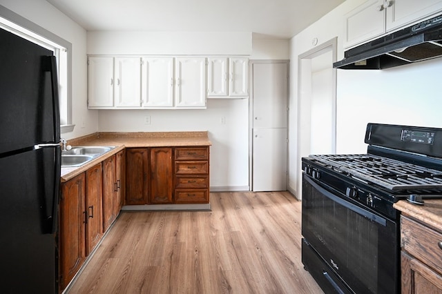 3114 Thomas Ave, Midland, TX 79701 - kitchen featuring black appliances, under cabinet range hood, white cabinets, light wood-style flooring, and brown cabinetry