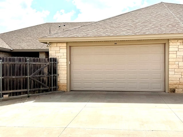 garage featuring fence, a gate, and concrete driveway