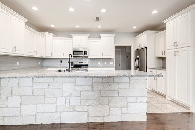 kitchen featuring decorative backsplash, white cabinetry, stainless steel appliances, and recessed lighting