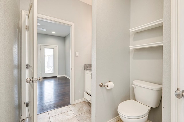 half bathroom featuring tile patterned flooring, toilet, vanity, and baseboards