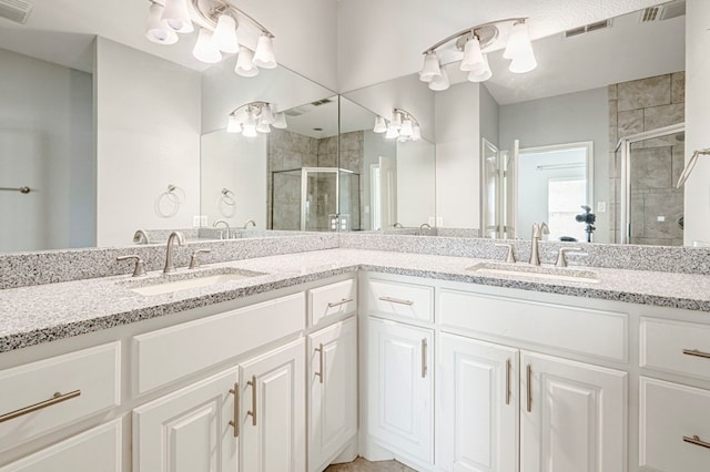 bathroom with double vanity, visible vents, a stall shower, and a sink