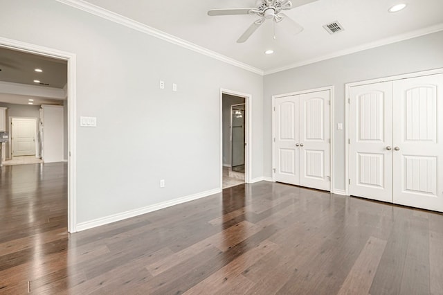 unfurnished bedroom featuring baseboards, visible vents, two closets, and crown molding