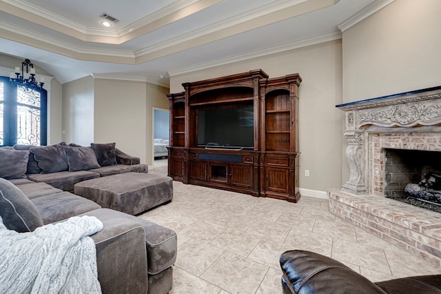 living room featuring visible vents, ornamental molding, a brick fireplace, baseboards, and a tray ceiling
