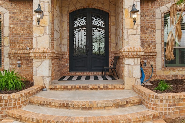 doorway to property featuring stone siding and brick siding