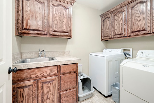 laundry area with a sink, washer and clothes dryer, cabinet space, and light tile patterned floors