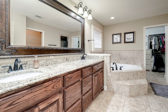 bathroom with double vanity, a walk in closet, visible vents, and a sink