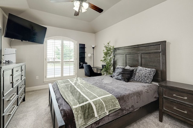 bedroom with a raised ceiling, baseboards, light carpet, and a ceiling fan
