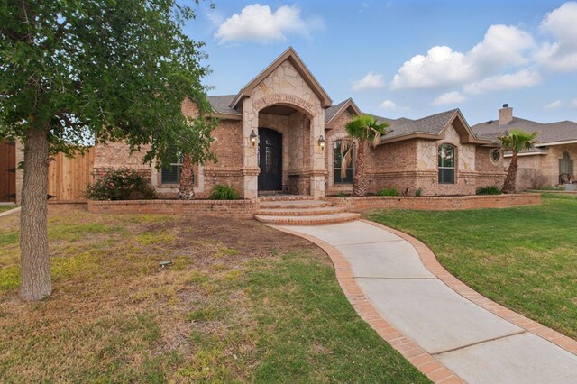 view of front of house with brick siding, fence, stone siding, and a front lawn
