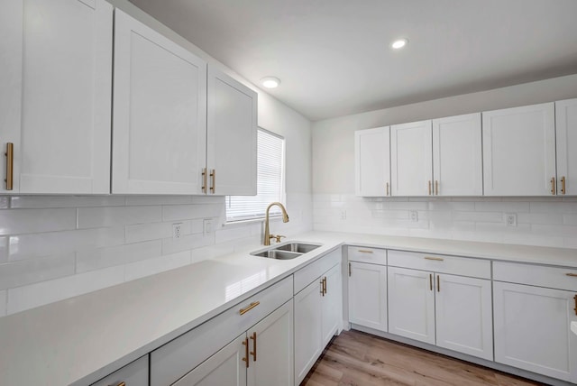 kitchen with light hardwood / wood-style floors, sink, decorative backsplash, and white cabinets