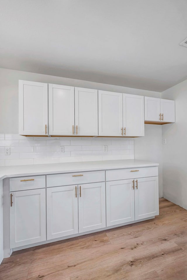 kitchen with white cabinetry, tasteful backsplash, and light hardwood / wood-style floors