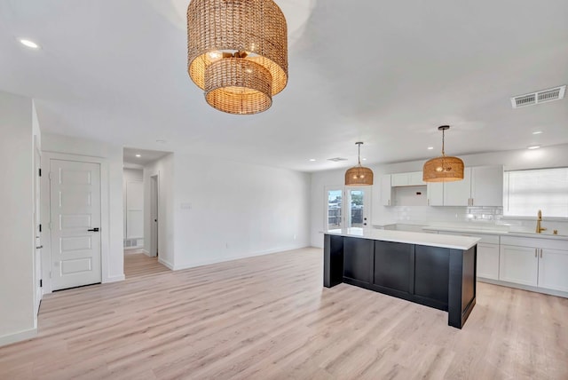 kitchen with sink, white cabinetry, tasteful backsplash, a center island, and hanging light fixtures