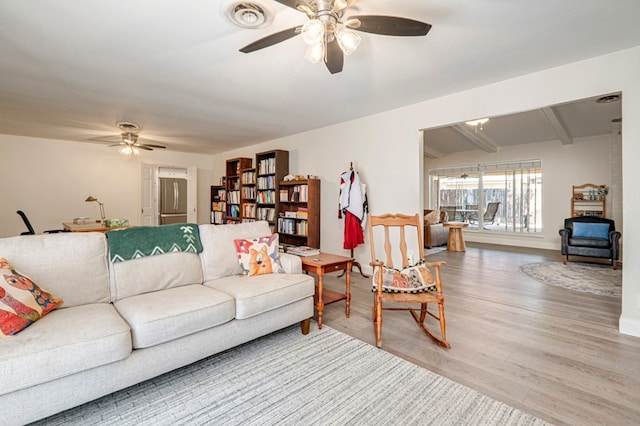 living area featuring visible vents, beam ceiling, baseboards, light wood-style flooring, and ceiling fan