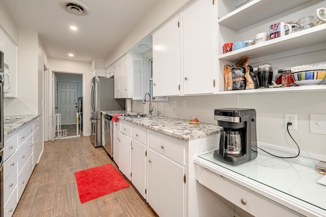 kitchen with a sink, dishwasher, light wood finished floors, white cabinets, and visible vents