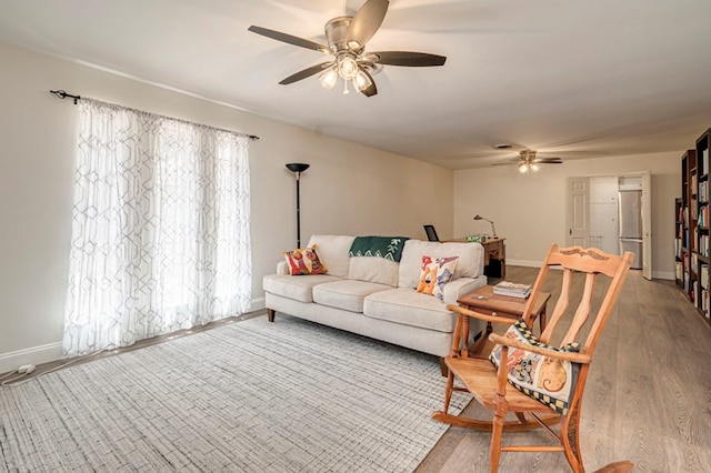 living room featuring ceiling fan, baseboards, and wood finished floors