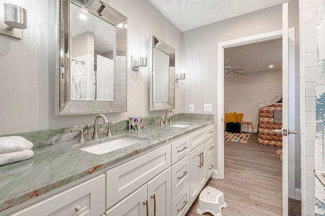 bathroom with a ceiling fan, wood finished floors, a sink, and double vanity