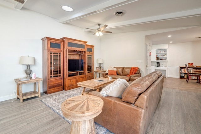 living room featuring ceiling fan, beamed ceiling, visible vents, and light wood-type flooring