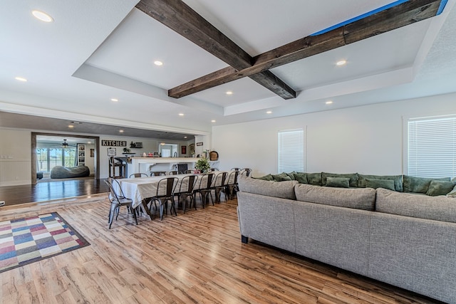 living room featuring beam ceiling, light hardwood / wood-style floors, and ceiling fan