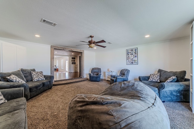 living room featuring a textured ceiling, carpet floors, ceiling fan, and ornamental molding