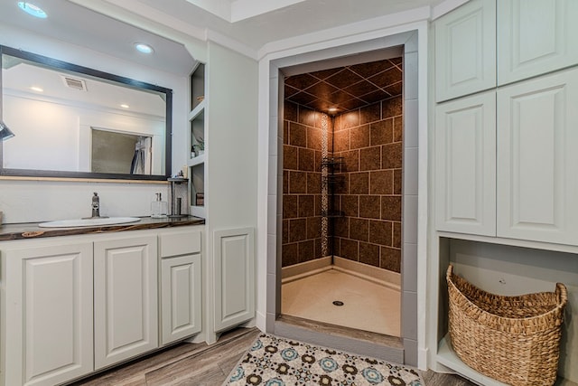 bathroom with a tile shower, vanity, and hardwood / wood-style flooring