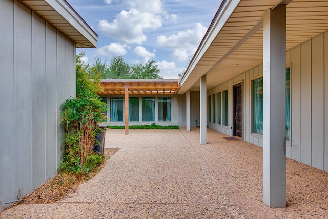 exterior space with board and batten siding, a patio area, and a pergola