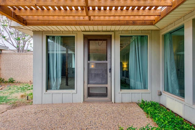 property entrance with board and batten siding and a pergola