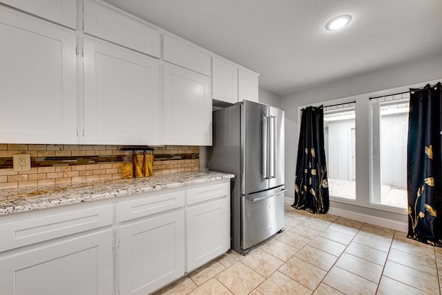 kitchen featuring high end refrigerator, white cabinetry, light tile patterned floors, and tasteful backsplash