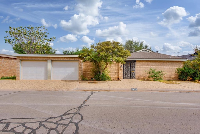 ranch-style house featuring brick siding, an attached garage, and driveway