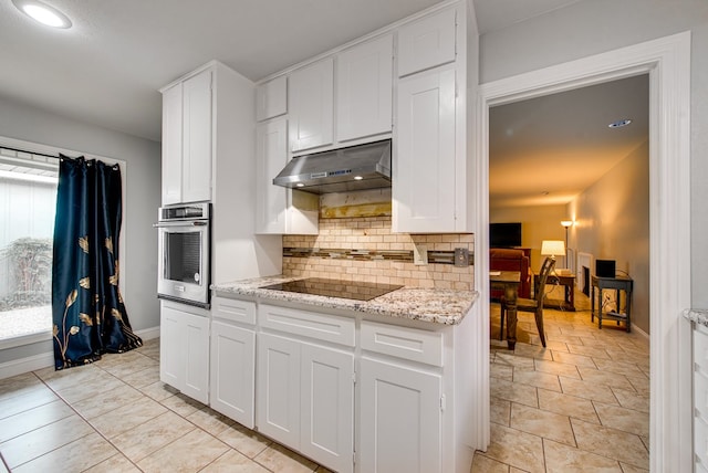 kitchen featuring backsplash, black electric cooktop, white cabinets, under cabinet range hood, and stainless steel oven