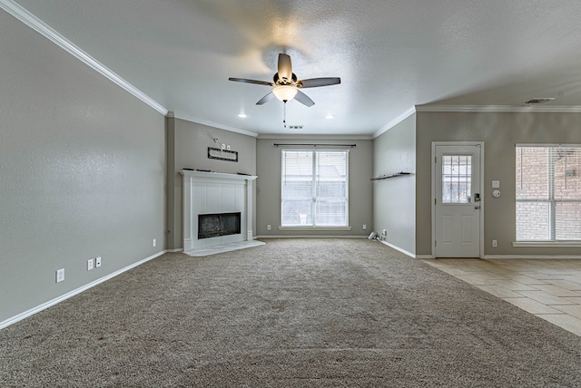 unfurnished living room with crown molding, a ceiling fan, carpet floors, and a tiled fireplace