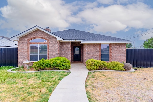 ranch-style home featuring fence, a shingled roof, a front lawn, brick siding, and a chimney