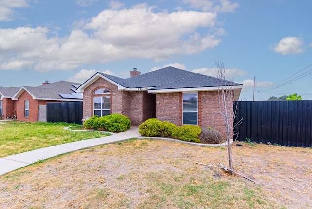 ranch-style house with brick siding, fence, and a front lawn