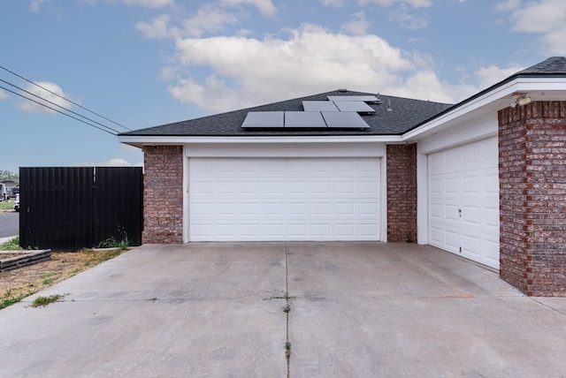 garage with fence and roof mounted solar panels