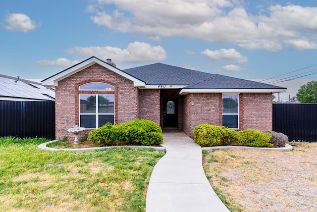 single story home with fence, a front lawn, and brick siding