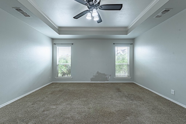 empty room featuring crown molding, visible vents, carpet floors, and a raised ceiling